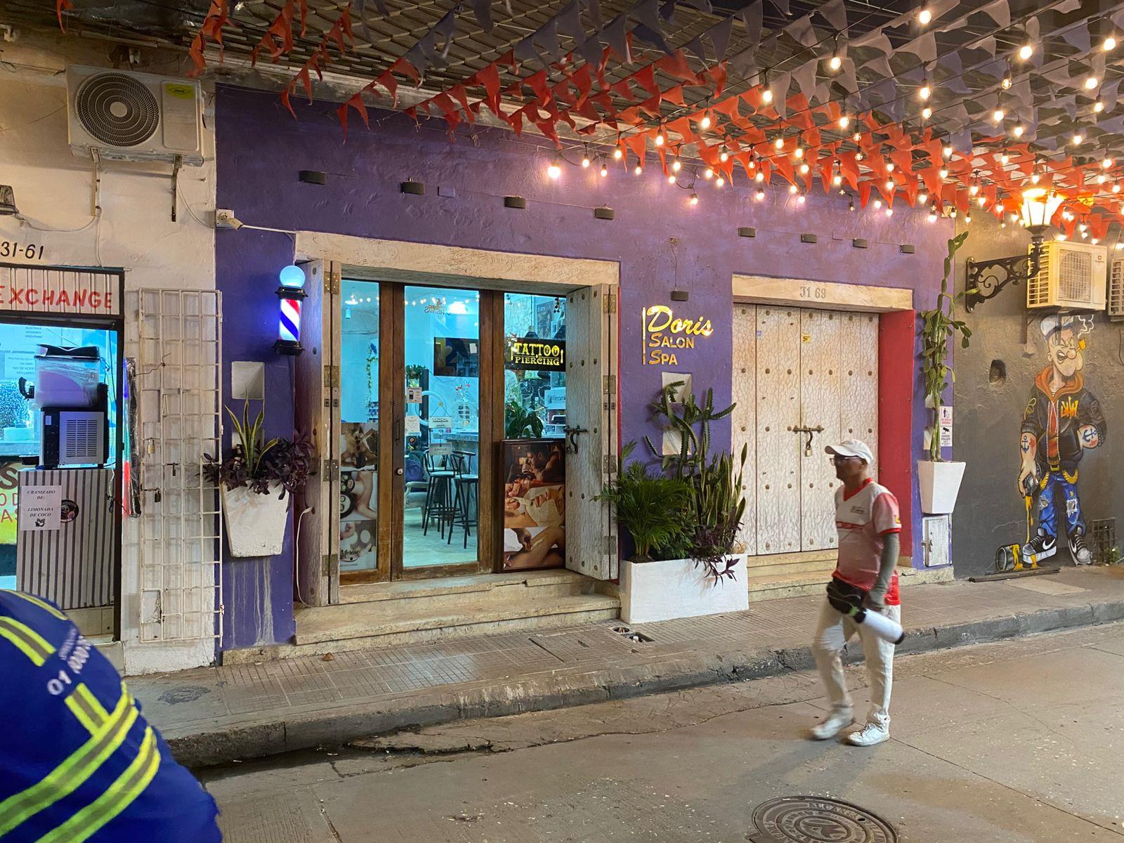 Fachada morada de Doris Salón Spa en Getsemaní, con banderines naranjas, bombillos, poste de barbero y el letrero dorado